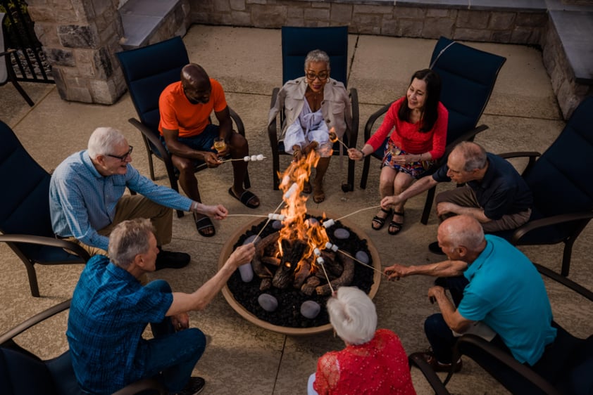 Group of seniors roasting marshmallows over an outdoor firepit